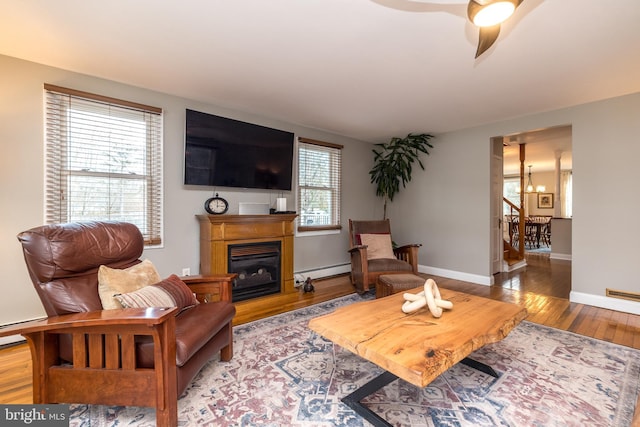 living room featuring ceiling fan with notable chandelier, light wood-type flooring, and baseboard heating