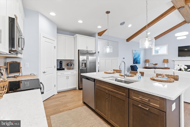 kitchen featuring sink, white cabinets, hanging light fixtures, stainless steel appliances, and a center island with sink