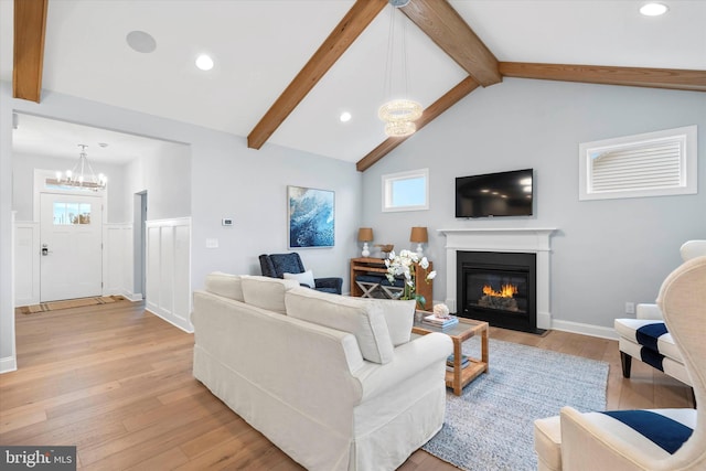 living room featuring vaulted ceiling with beams, a notable chandelier, and light wood-type flooring