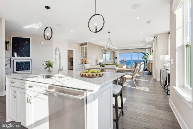 kitchen featuring white cabinetry, an island with sink, sink, a breakfast bar area, and stainless steel dishwasher