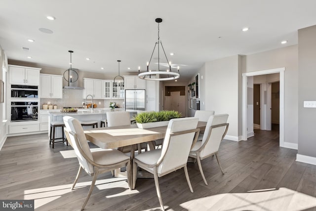 dining room with dark hardwood / wood-style flooring, sink, and an inviting chandelier