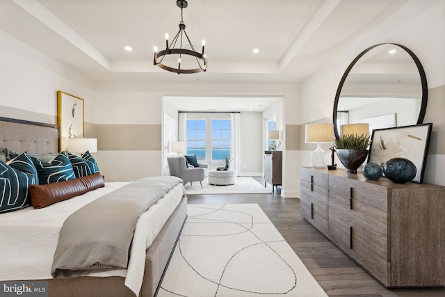 bedroom with a tray ceiling, dark hardwood / wood-style floors, and a chandelier