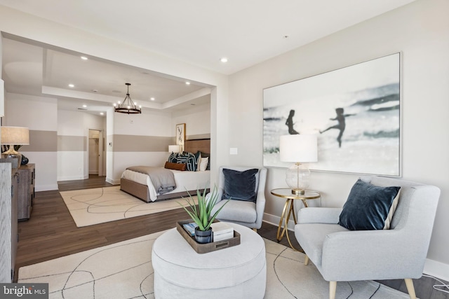 bedroom featuring an inviting chandelier, a raised ceiling, and hardwood / wood-style floors