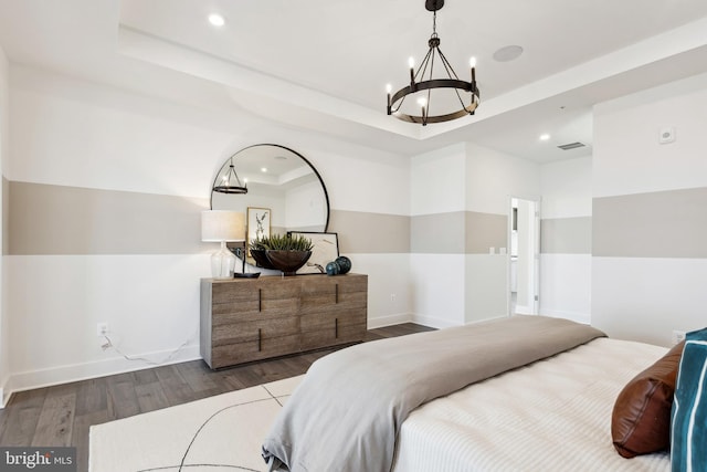 bedroom featuring a chandelier, a tray ceiling, and dark hardwood / wood-style flooring