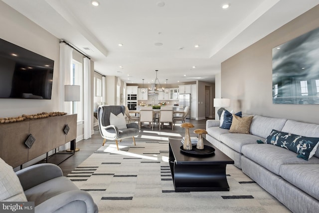 living room with sink, a tray ceiling, and light hardwood / wood-style floors