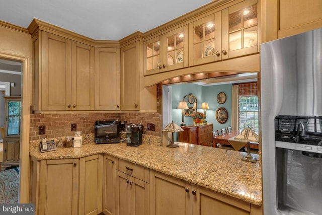 kitchen featuring stainless steel fridge, light brown cabinetry, and decorative backsplash