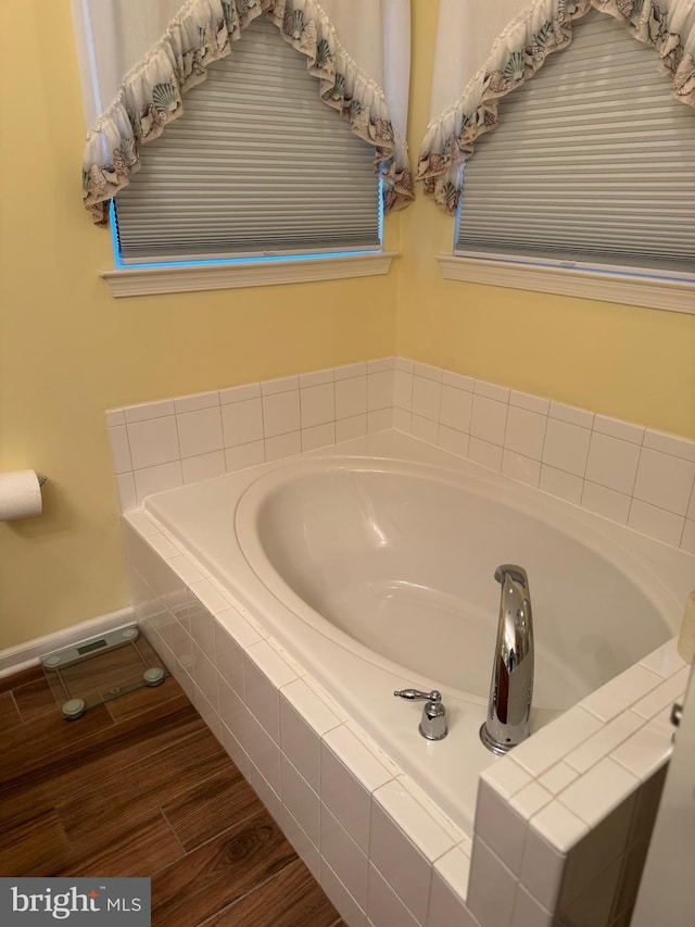 bathroom featuring tiled tub and hardwood / wood-style floors