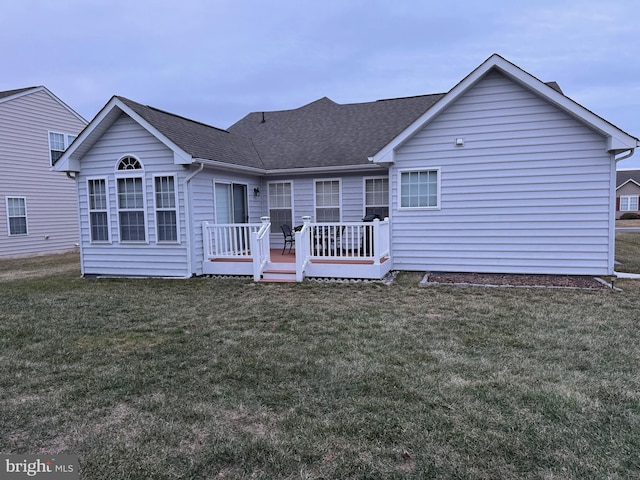 rear view of property with a deck and a lawn