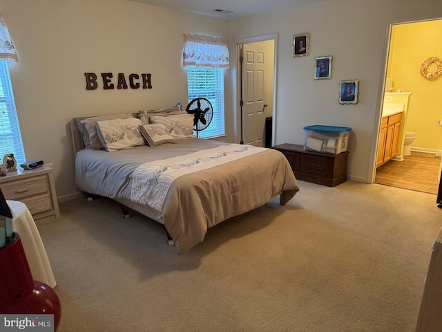 bedroom featuring ensuite bathroom and light carpet