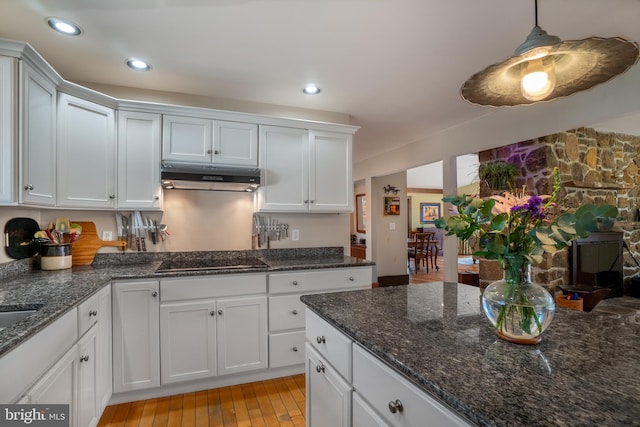 kitchen featuring pendant lighting, light wood-style floors, white cabinetry, under cabinet range hood, and black electric cooktop