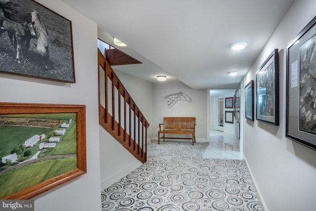 hallway featuring stairway, baseboards, and light tile patterned flooring