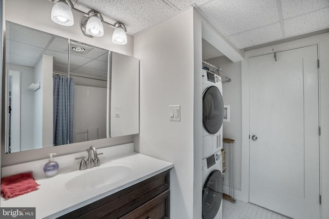 full bathroom with a shower with shower curtain, stacked washer and dryer, a drop ceiling, and vanity