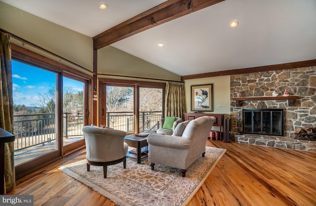 living area featuring vaulted ceiling with beams, a stone fireplace, wood finished floors, and recessed lighting