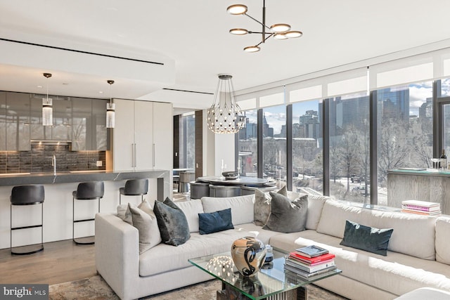 living room with an inviting chandelier, sink, a wall of windows, and light hardwood / wood-style floors