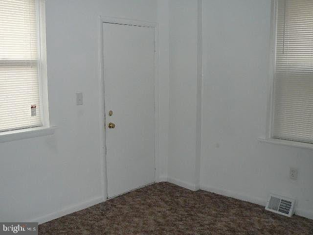 spare room featuring dark carpet