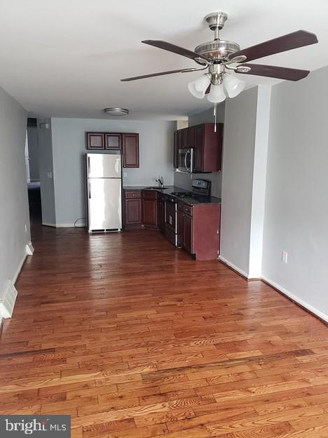 kitchen featuring wood-type flooring, sink, fridge, stove, and ceiling fan