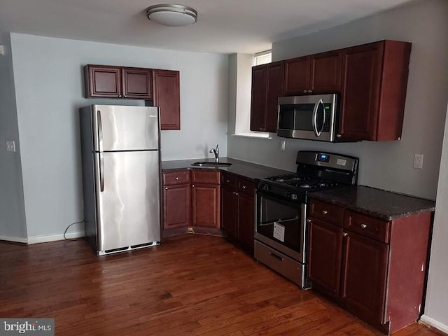 kitchen with appliances with stainless steel finishes, dark wood-type flooring, and sink