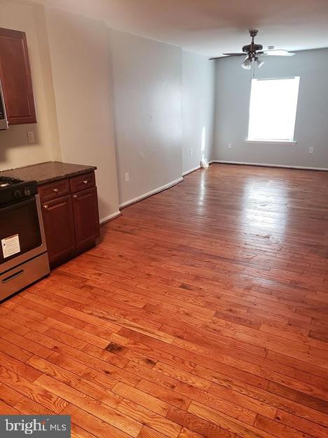 kitchen with gas range, dark brown cabinets, ceiling fan, and light wood-type flooring