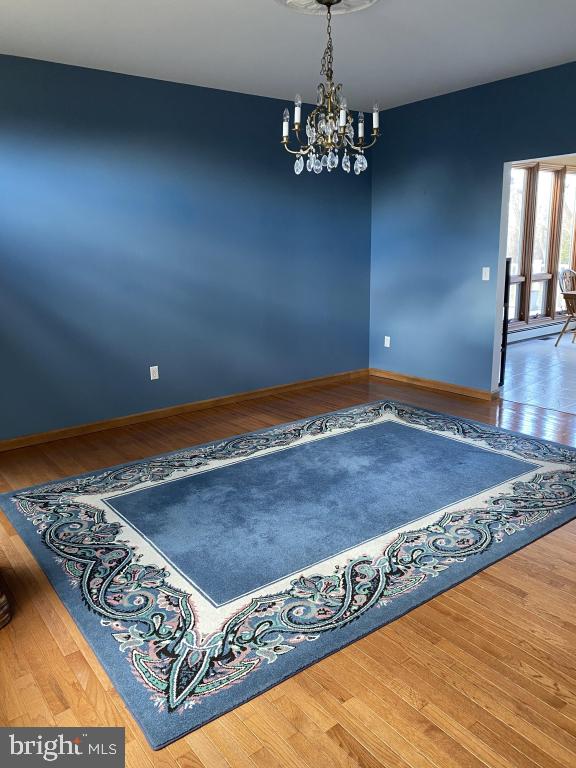 spare room featuring hardwood / wood-style flooring and a notable chandelier