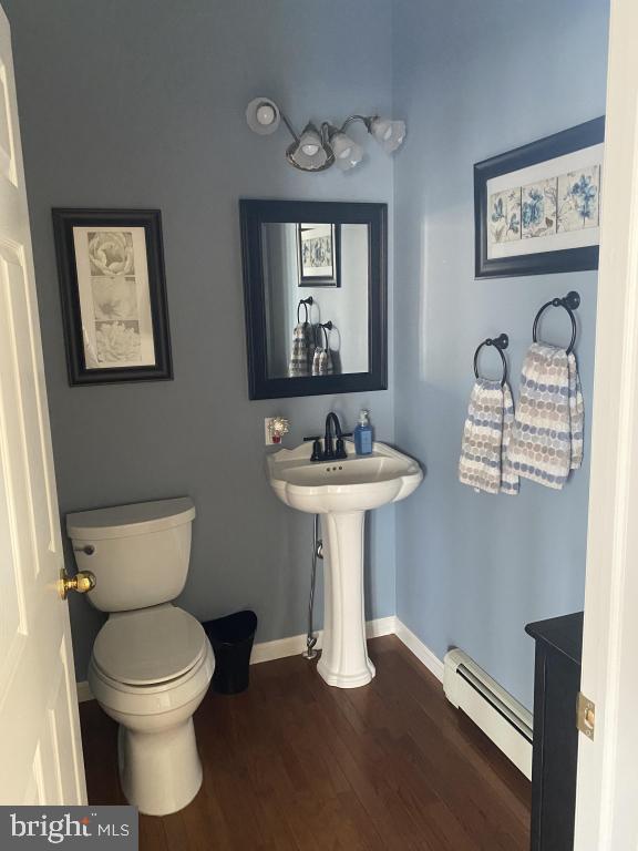 bathroom with a baseboard heating unit, wood-type flooring, sink, and toilet