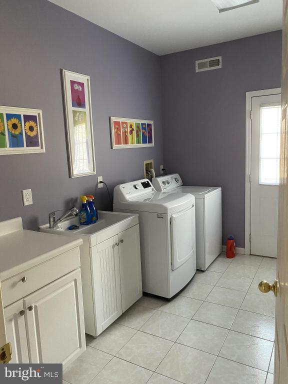 clothes washing area featuring cabinets, sink, light tile patterned floors, and independent washer and dryer