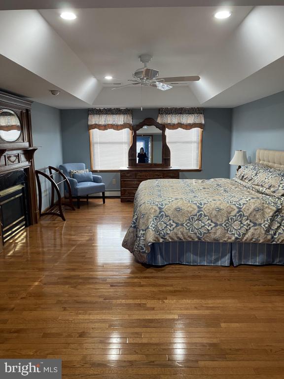 bedroom featuring hardwood / wood-style flooring, vaulted ceiling, ceiling fan, and multiple windows