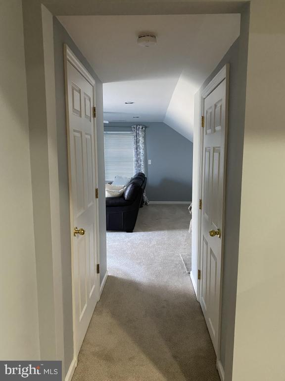 corridor with light colored carpet and lofted ceiling