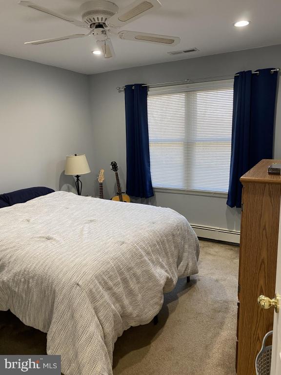 bedroom with a baseboard radiator, ceiling fan, and carpet flooring