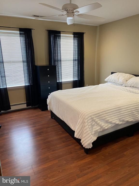 bedroom with multiple windows, dark hardwood / wood-style floors, and ceiling fan