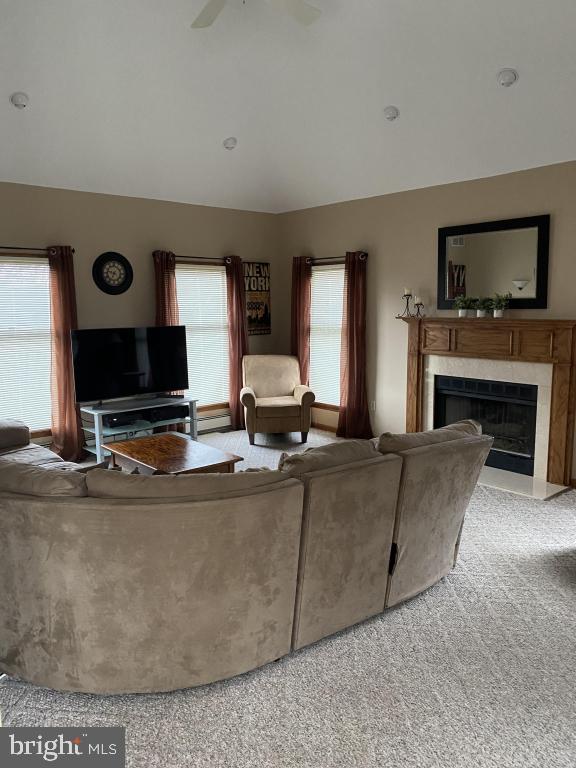 living room featuring lofted ceiling, a fireplace, light colored carpet, and ceiling fan