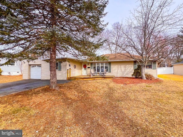 single story home featuring covered porch, an attached garage, fence, driveway, and a front lawn