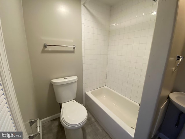 bathroom with tiled shower / bath, tile patterned floors, and toilet