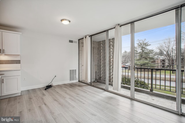 spare room with light hardwood / wood-style flooring and floor to ceiling windows