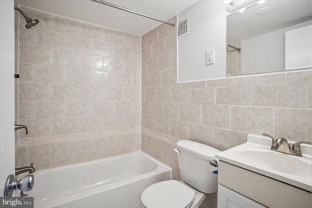 full bathroom featuring tiled shower / bath combo, vanity, tile walls, and toilet