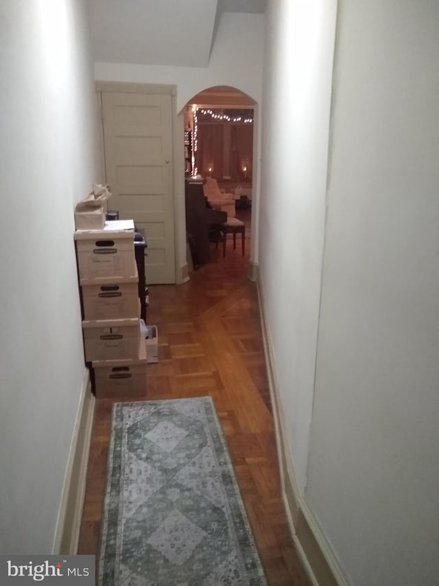 corridor with baseboards and arched walkways