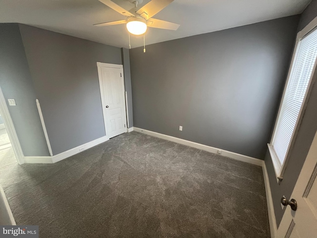 unfurnished room with dark carpet and ceiling fan