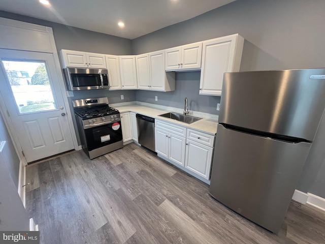 kitchen featuring appliances with stainless steel finishes, sink, white cabinets, and light hardwood / wood-style floors