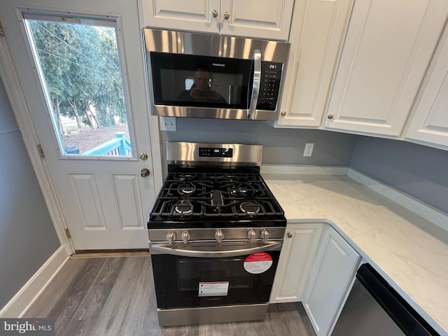 kitchen with appliances with stainless steel finishes, white cabinets, and dark hardwood / wood-style flooring