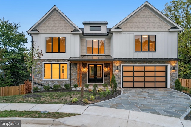 view of front facade with decorative driveway, a standing seam roof, fence, and a garage