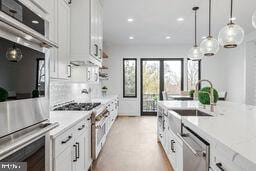 kitchen featuring stainless steel appliances, white cabinets, hanging light fixtures, and a sink