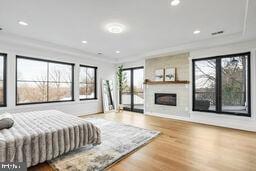 bedroom with ornamental molding, wood finished floors, access to outside, a fireplace, and recessed lighting