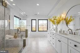 bathroom featuring recessed lighting, a sink, double vanity, a tub with marble appearance, and crown molding