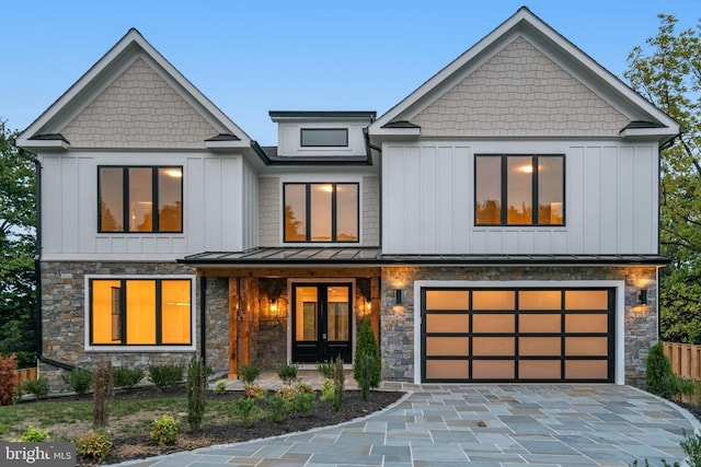 view of front of house with decorative driveway, board and batten siding, a standing seam roof, metal roof, and a garage