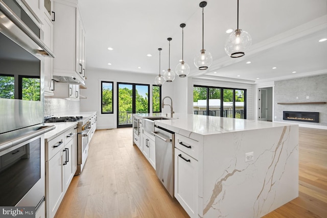 kitchen featuring light stone counters, a spacious island, white cabinetry, and decorative light fixtures