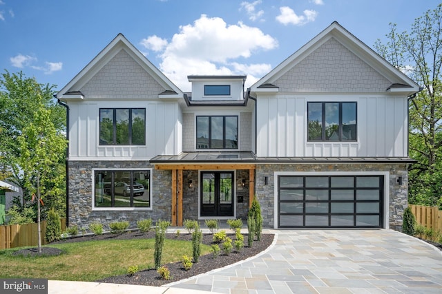 view of front facade featuring decorative driveway, board and batten siding, a standing seam roof, fence, and a garage