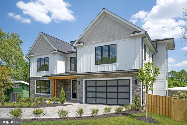 view of front of property with a garage, fence, driveway, stone siding, and board and batten siding