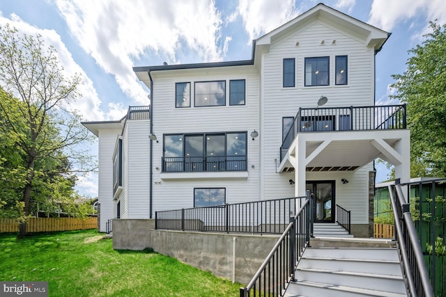 view of front of home with fence, a balcony, a front lawn, and stairs