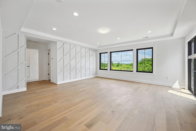 unfurnished living room with recessed lighting, visible vents, baseboards, light wood-type flooring, and a tray ceiling