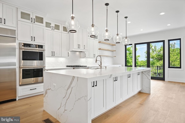 kitchen with a spacious island, white cabinetry, appliances with stainless steel finishes, tasteful backsplash, and glass insert cabinets