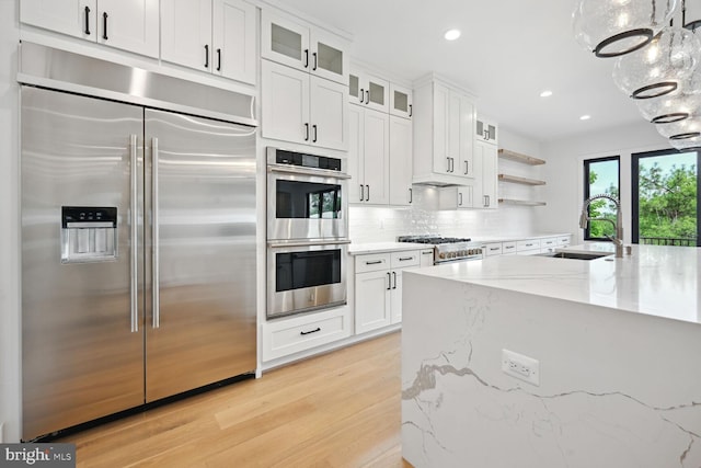 kitchen featuring hanging light fixtures, appliances with stainless steel finishes, a sink, and white cabinets